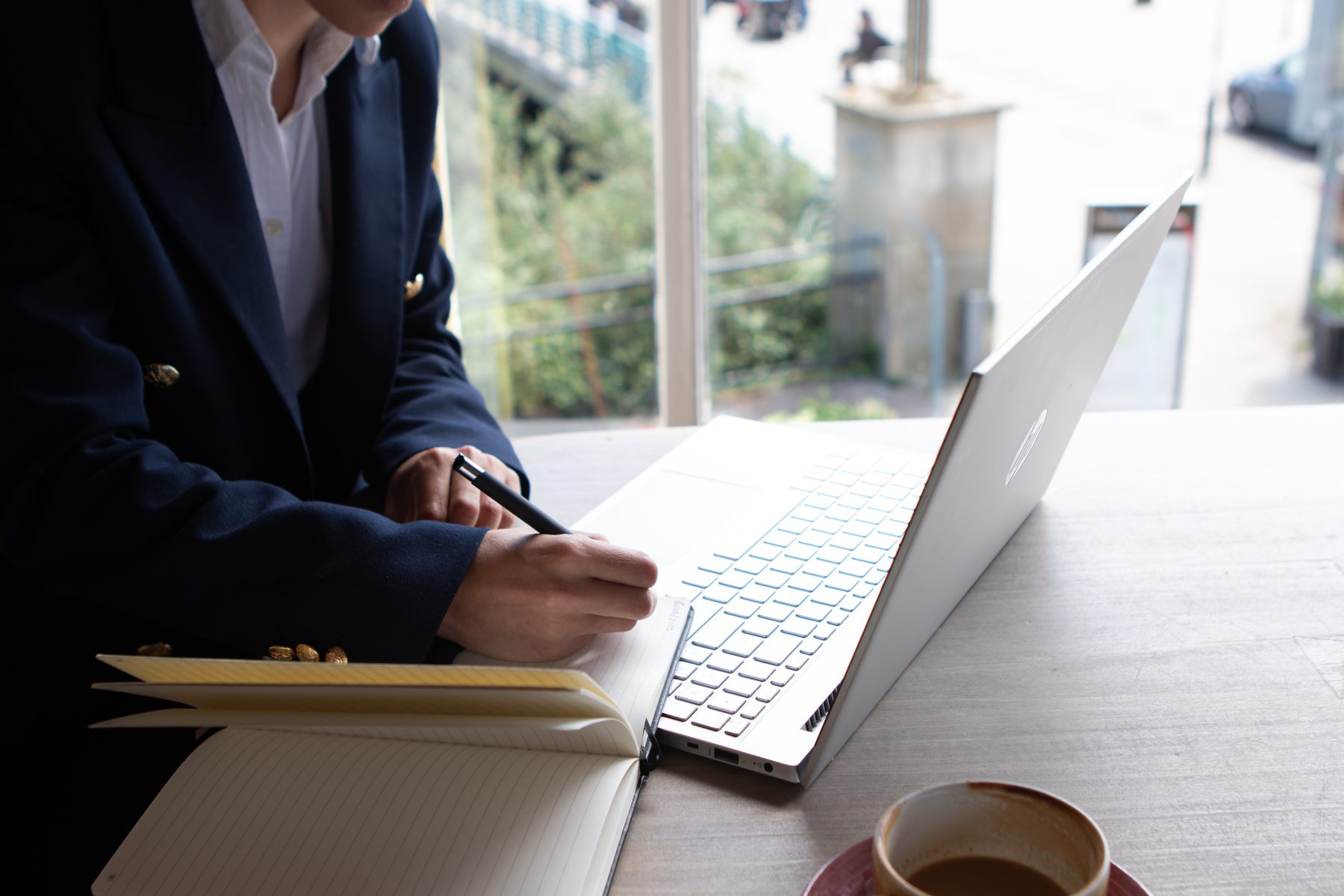 Coaching notes being written in a notebook beside a laptop during an online session